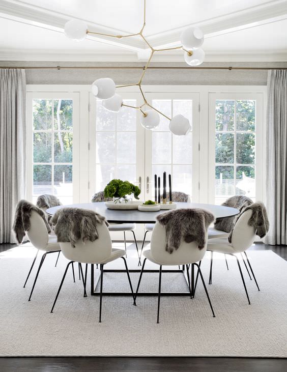 طراحی و دکوراسیون اتاق ناهار خوری با لوستر شاخه ای که از تعادل شعاعی برای چیدمان صندلی و میز در آن استفاده شده است